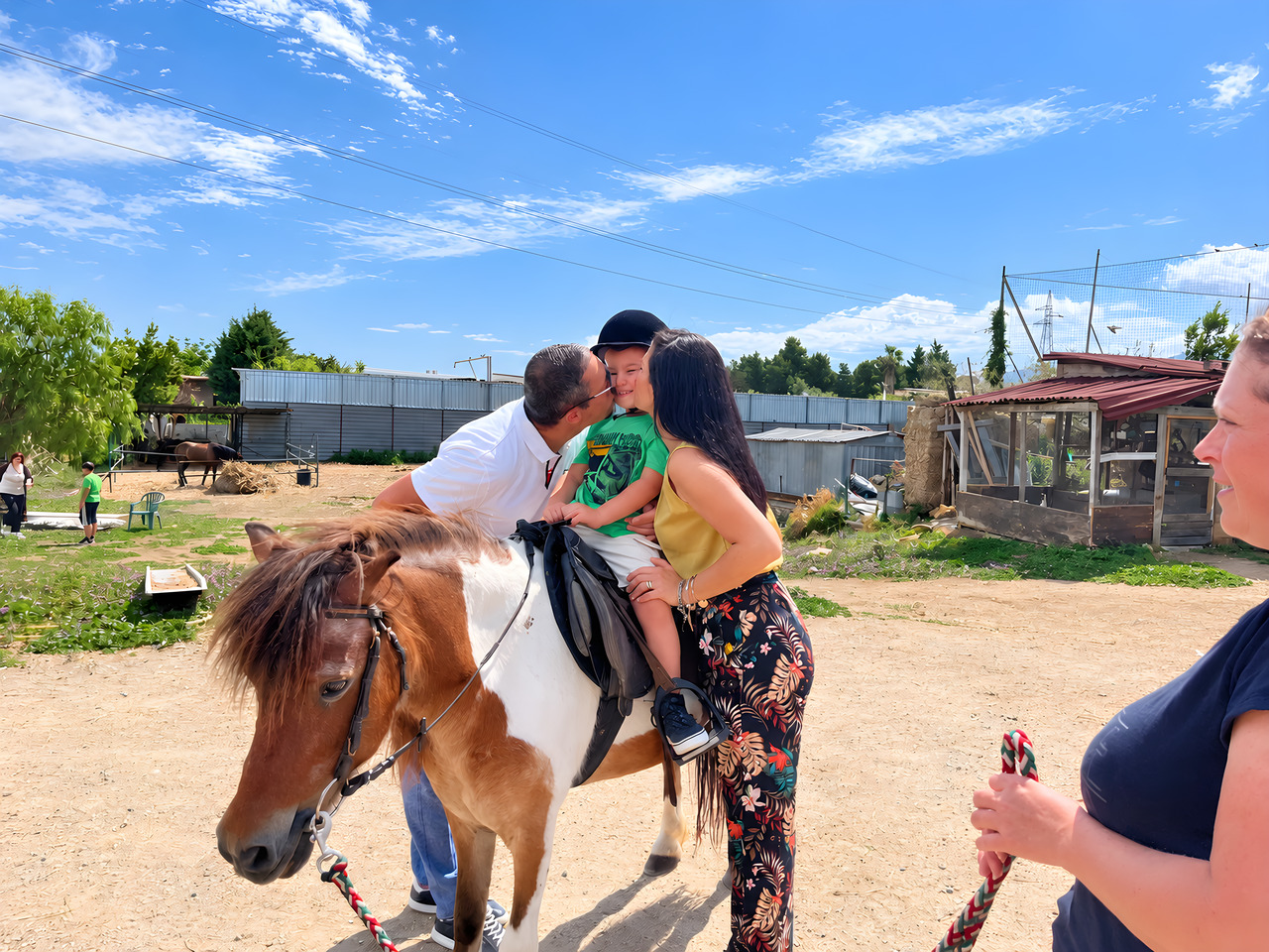 Un bambino su un pony pezzato, tenuto per mano da due adulti